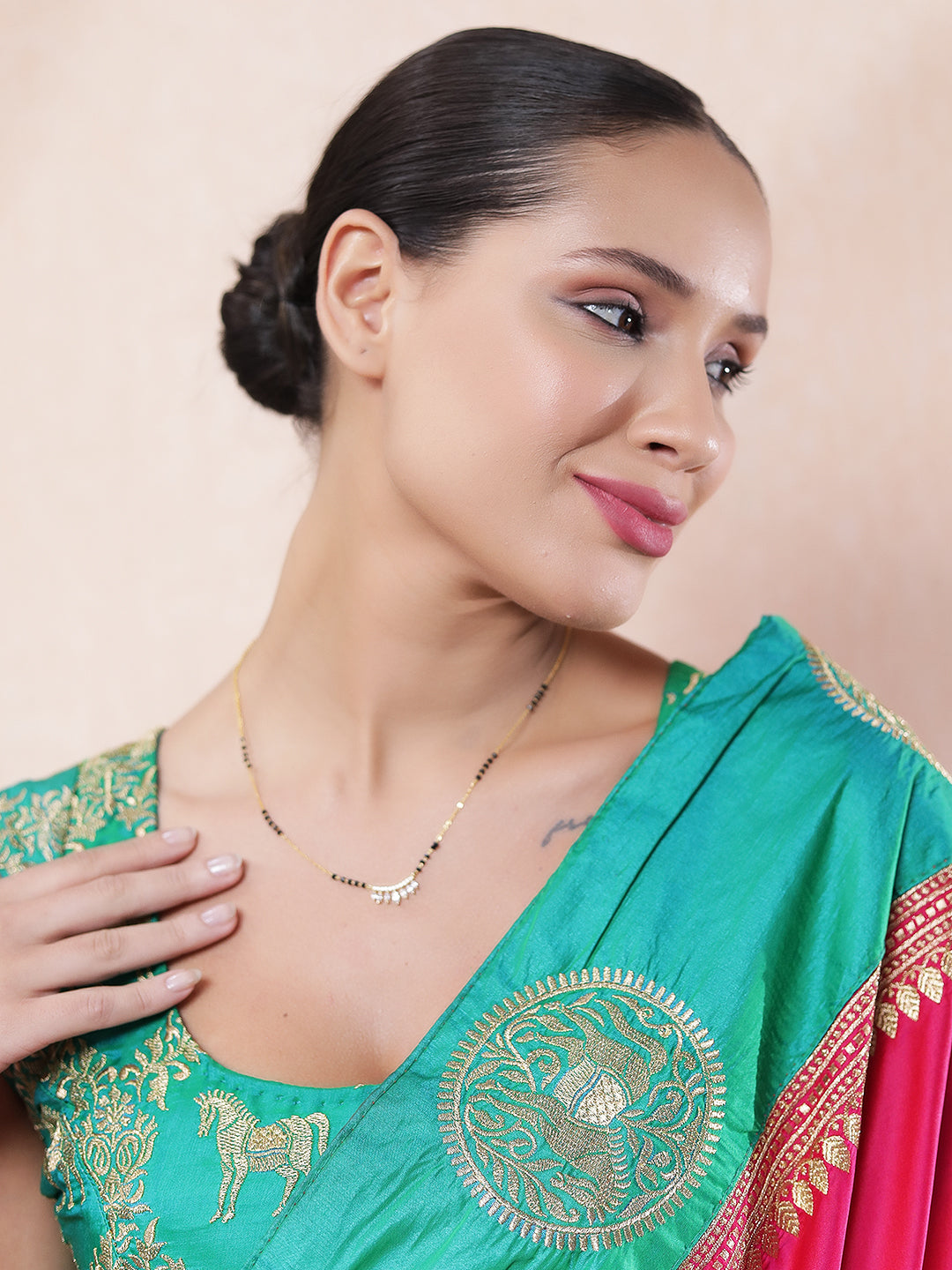 Woman wearing a traditional gold mangalsutra design with black beads and a sparkling CZ leaf-style pendant