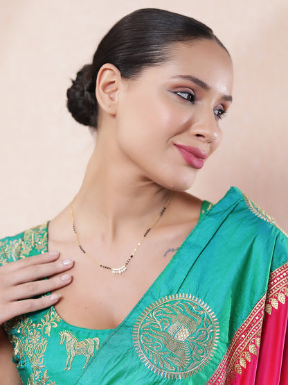 Woman wearing a traditional gold mangalsutra design with black beads and a sparkling CZ leaf-style pendant
