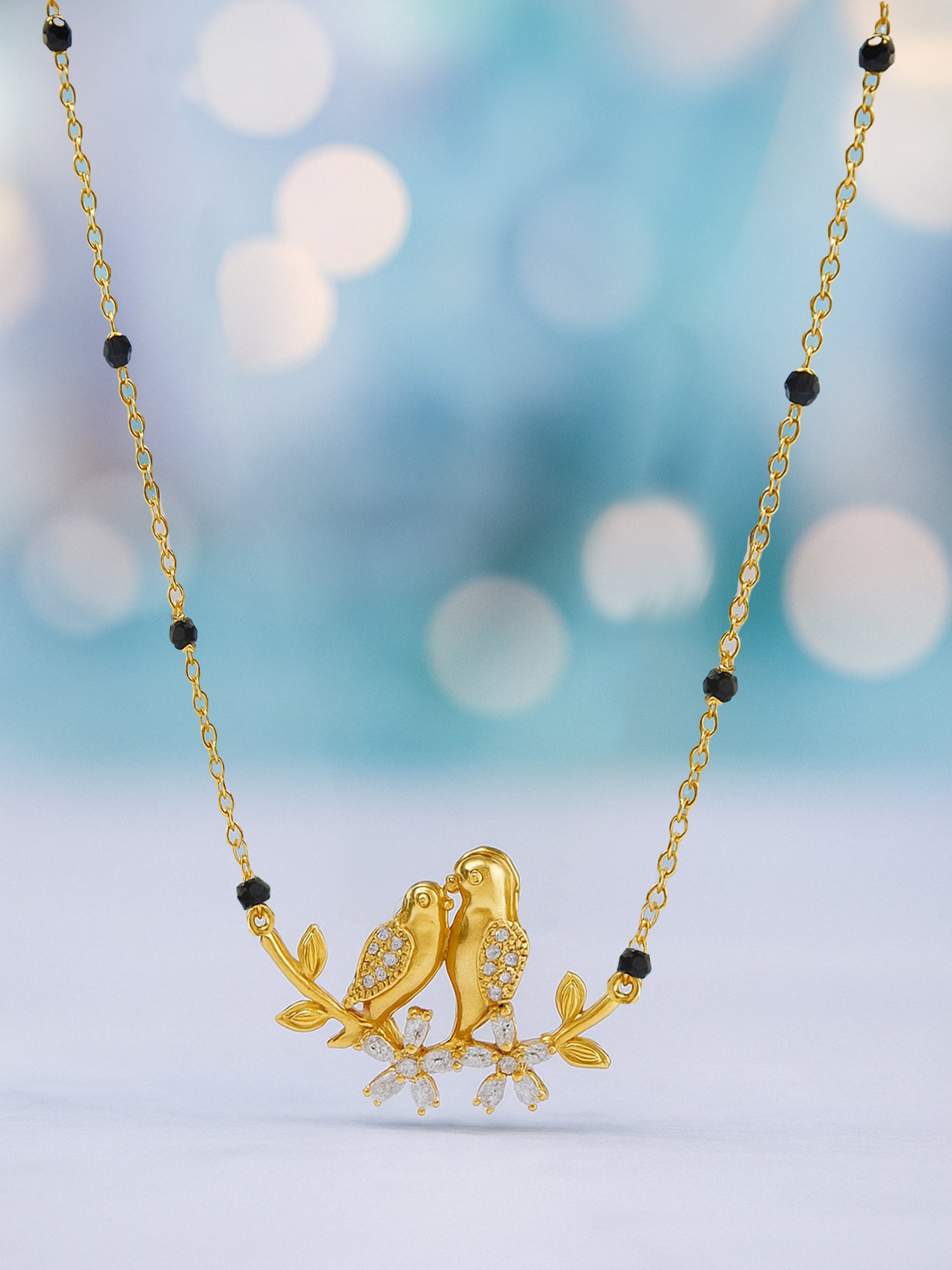Black beads mangalsutra gold necklace with delicate gold chain and a sparking CZ-studded bird and floral motif pendant