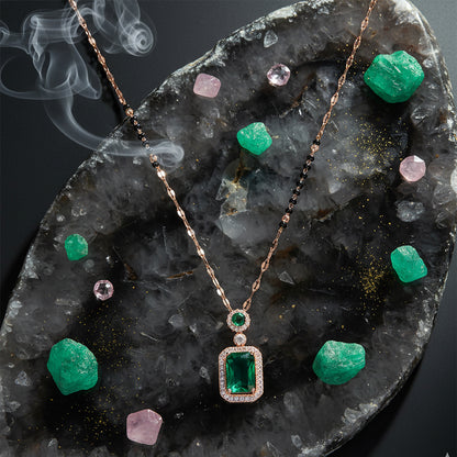 Gold black-beads mangalsutra with an emerald pendant displayed on a stone backdrop with green and pink crystals