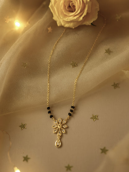 mangalsutra design featuring a sparkling diamond/CZ floral motif and teardrop pendant on a gold chain with black beads