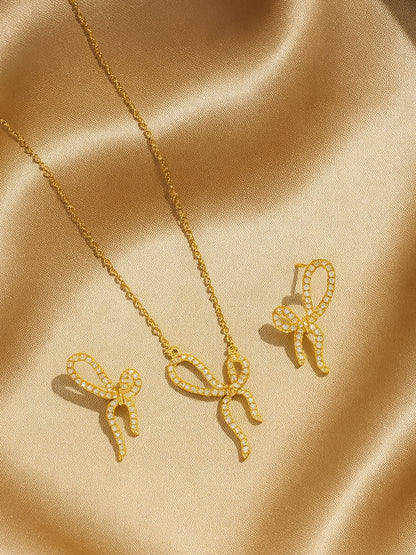 Close-up of a gold-tone bow-knot necklace pendant and matching earrings, featuring a crystal design.
