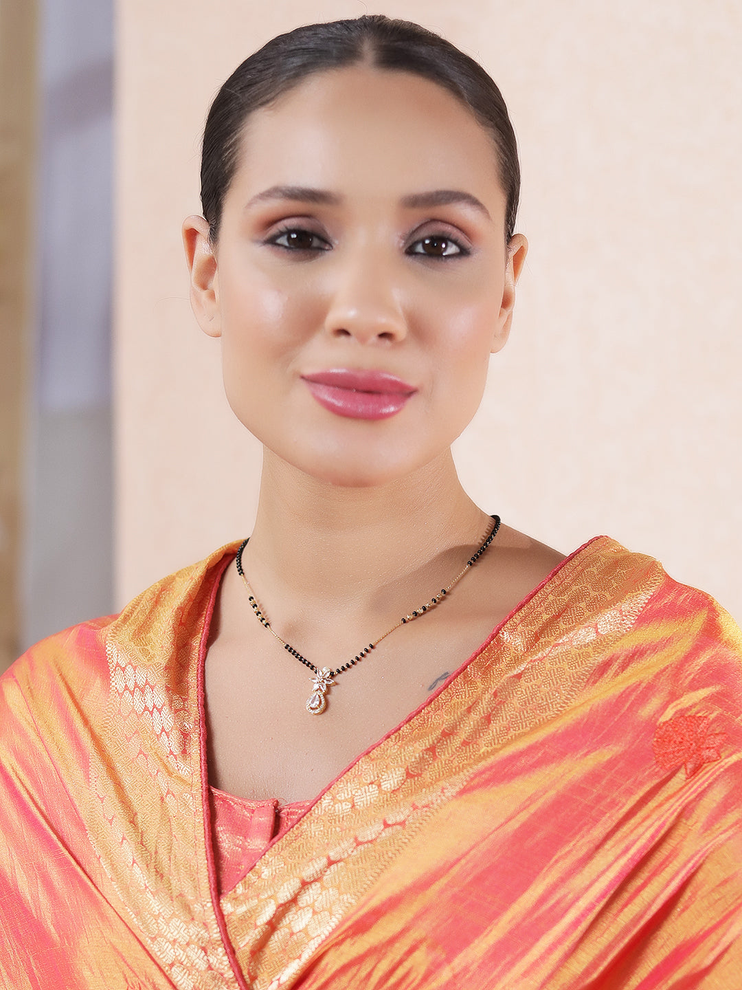 Model wearing a traditional mangalsutra design with black beads and a classic pendant