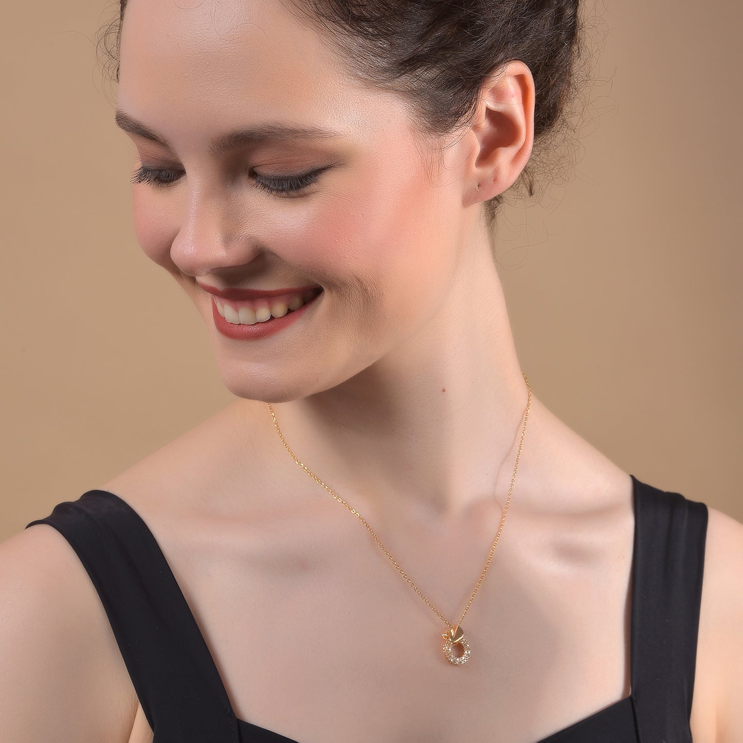 A woman showcasing one of the latest gold necklace designs featuring a delicate chain and a circular pendant 