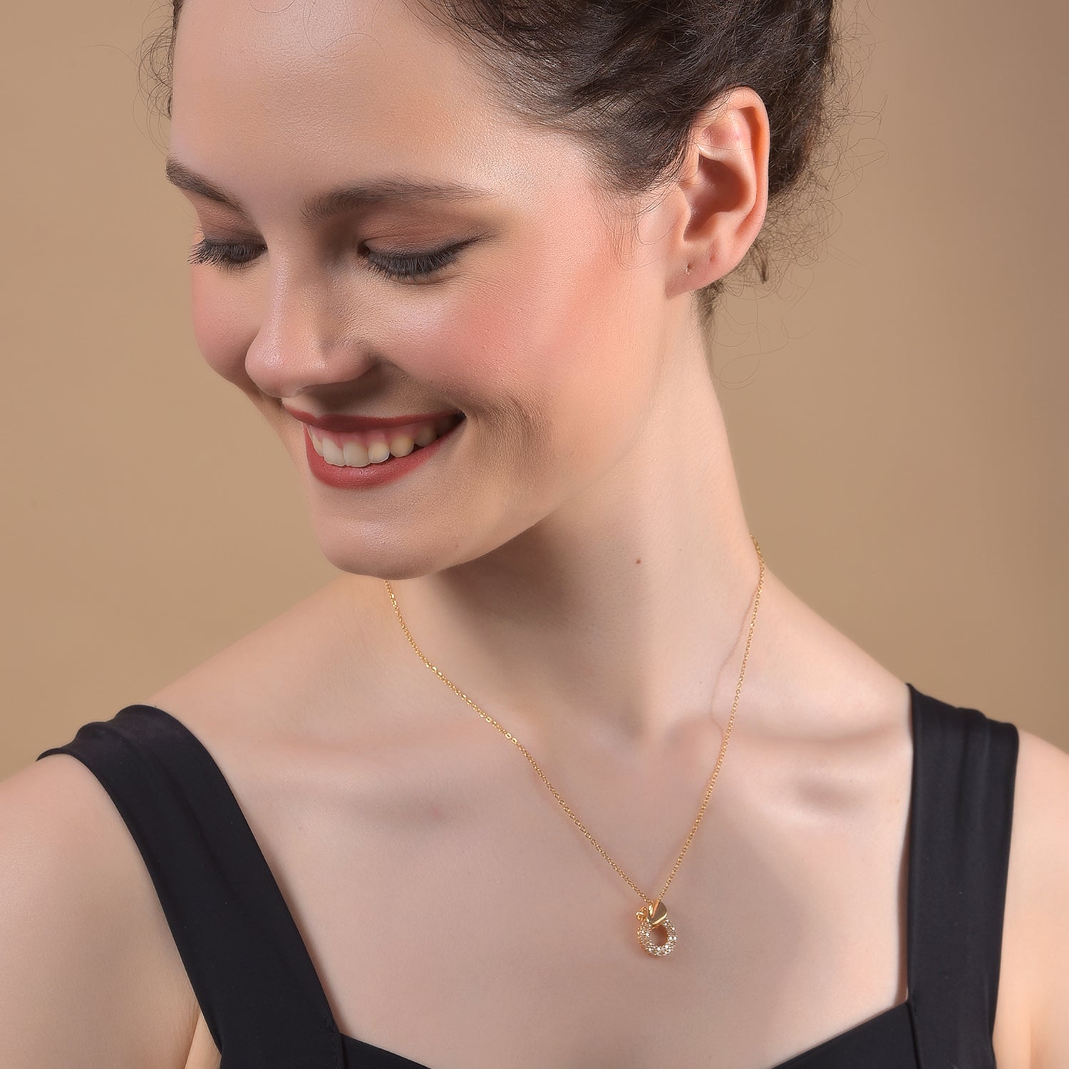 A woman showcasing one of the latest gold necklace designs featuring a delicate chain and a circular pendant 