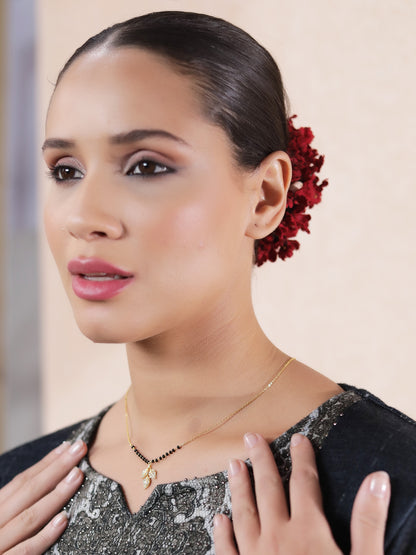 Woman wearing a daily wear mangalsutra design in gold featuring small black beads and a crystal leaf pendant