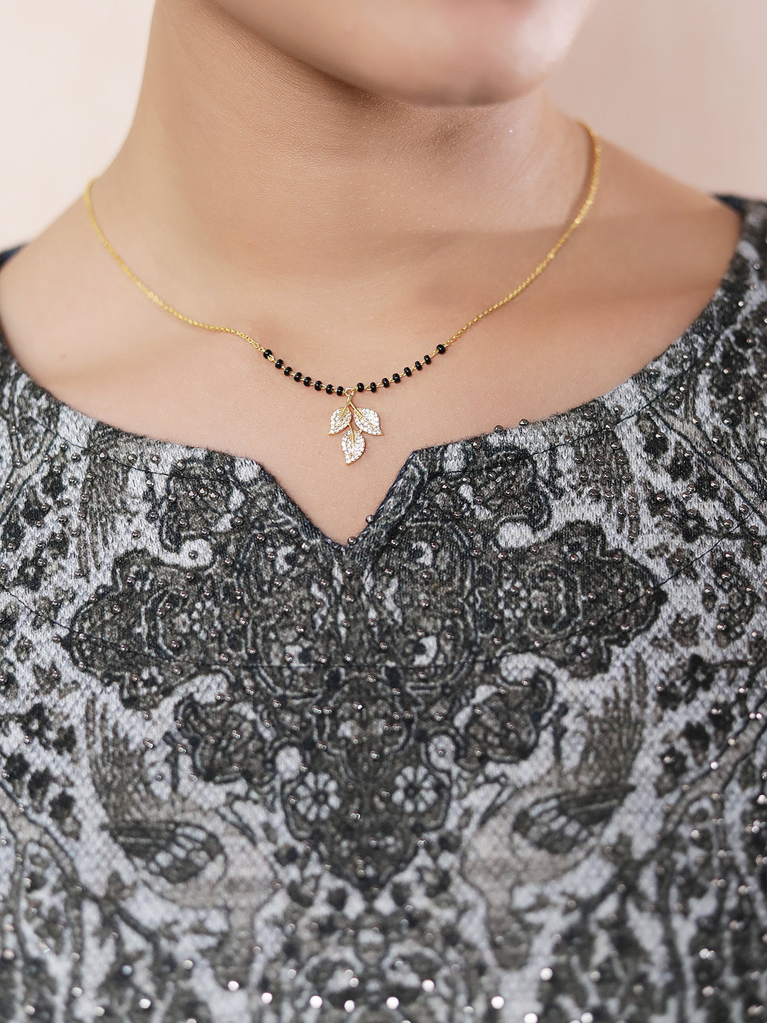 “Mangalsutra pendant design featuring traditional black beads and a gold chain with a crystal leaf pendant