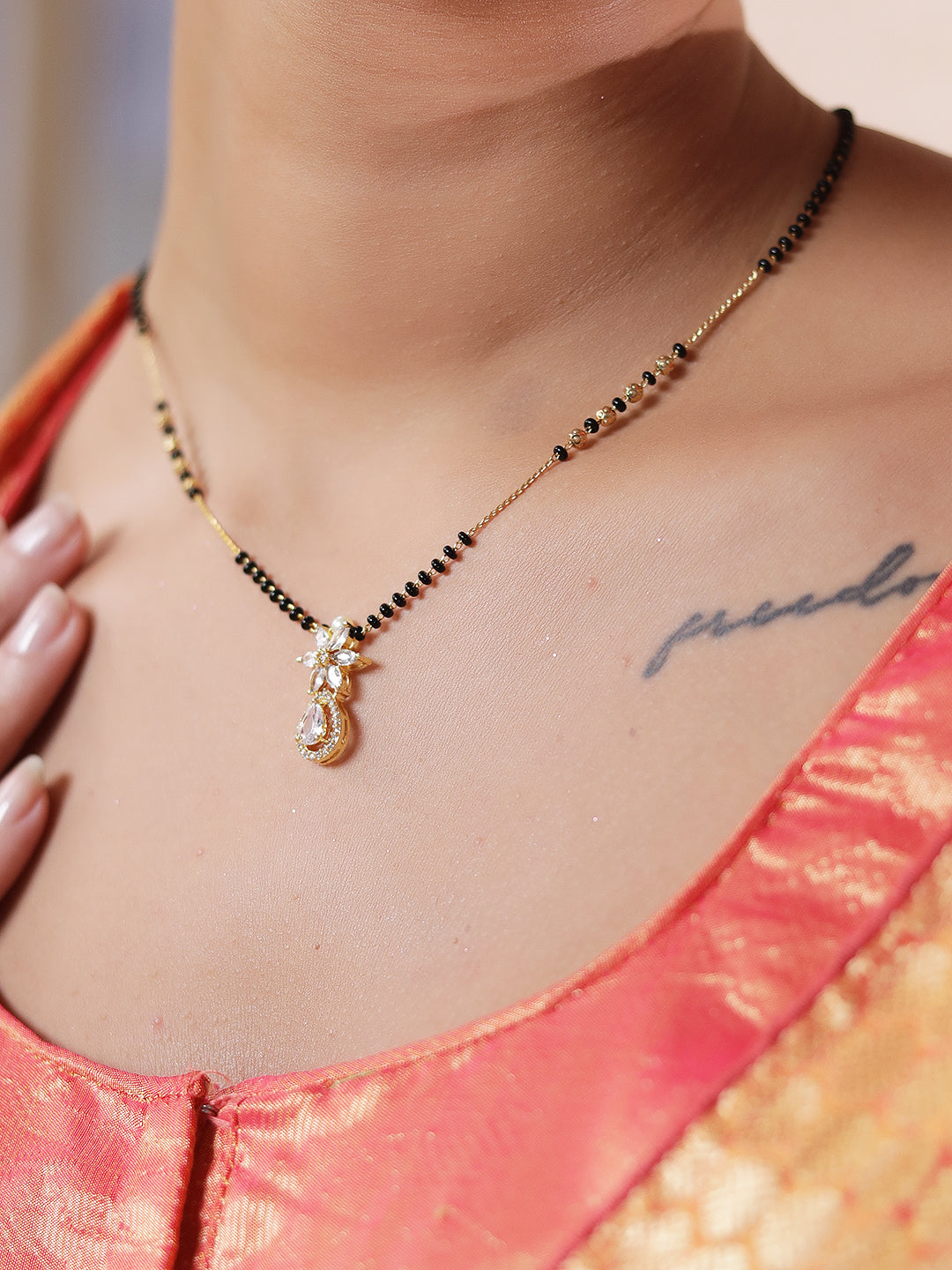 Daily wear mangalsutra design in gold with black beads and a small floral pendant