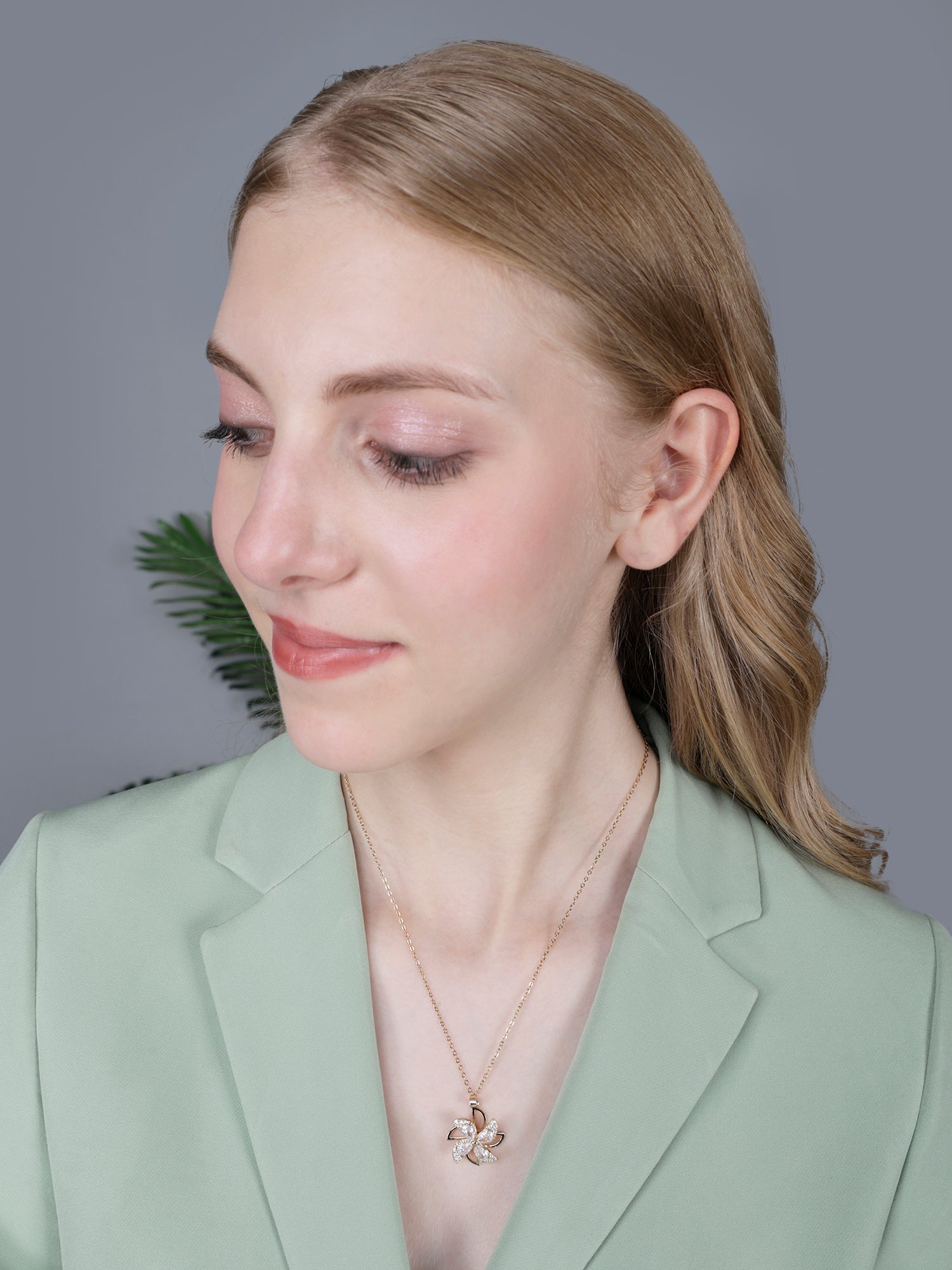 Modern gold necklace designs with a kinetic floral pendant displayed on a luxurious champagne-colored silk background with intricate embroidery