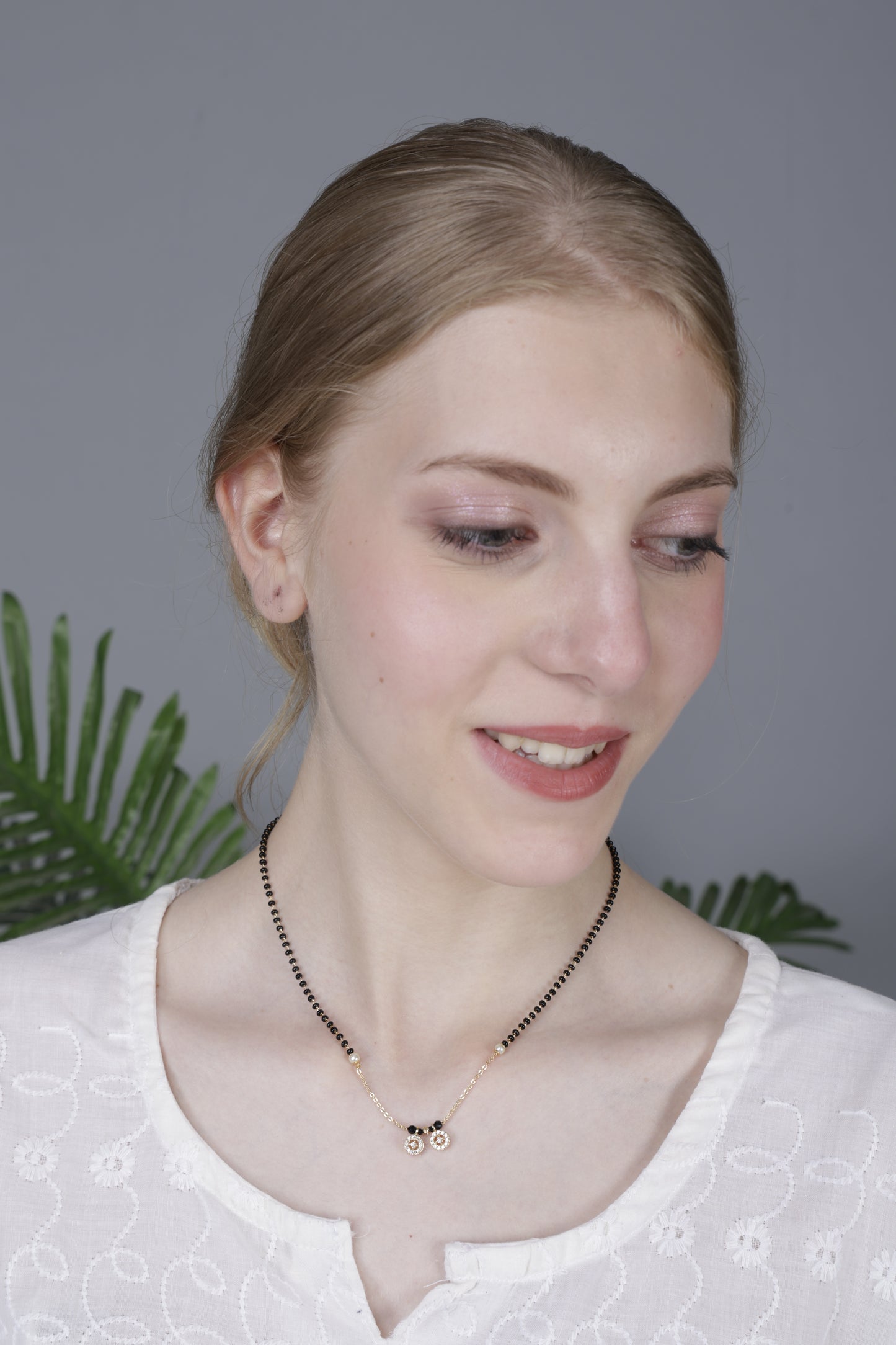 Gold mangalsutra with dual floral pendant on a black bead chain