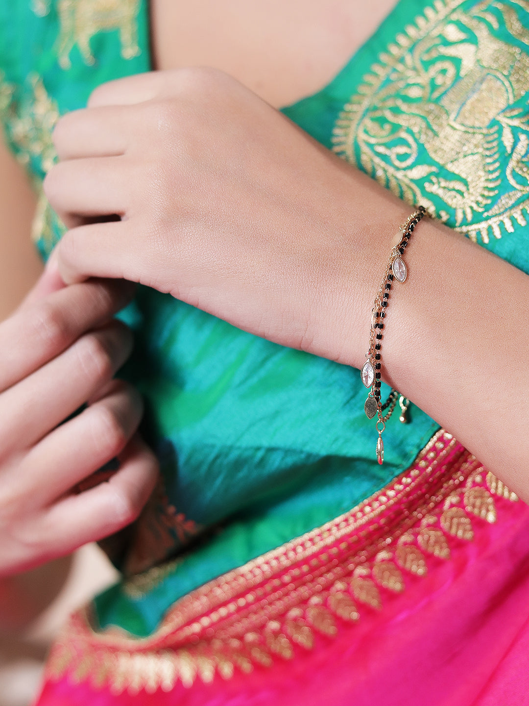 Elegant mangalsutra bracelet design with black beads and gold charms on a woman's wrist
