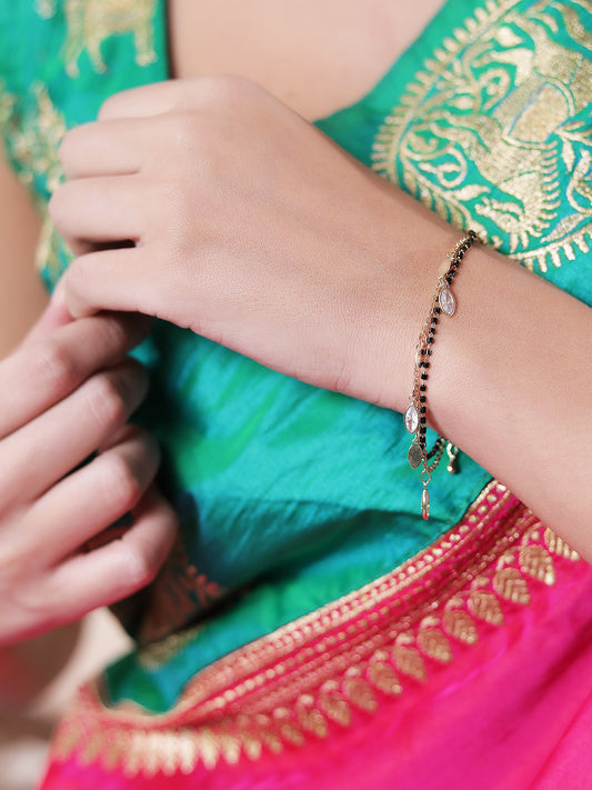 Elegant mangalsutra bracelet design with black beads and gold charms on a woman's wrist