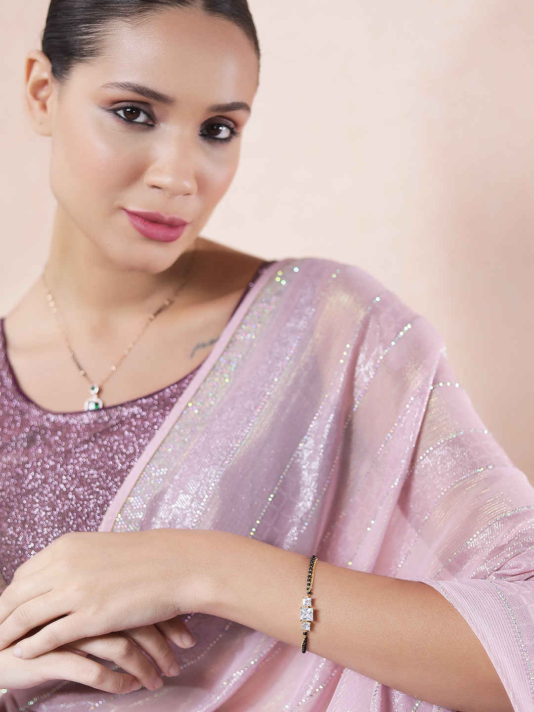 Woman wearing a diamond mangalsutra design paired with a shimmery pink saree, showcasing the matching bracelet.