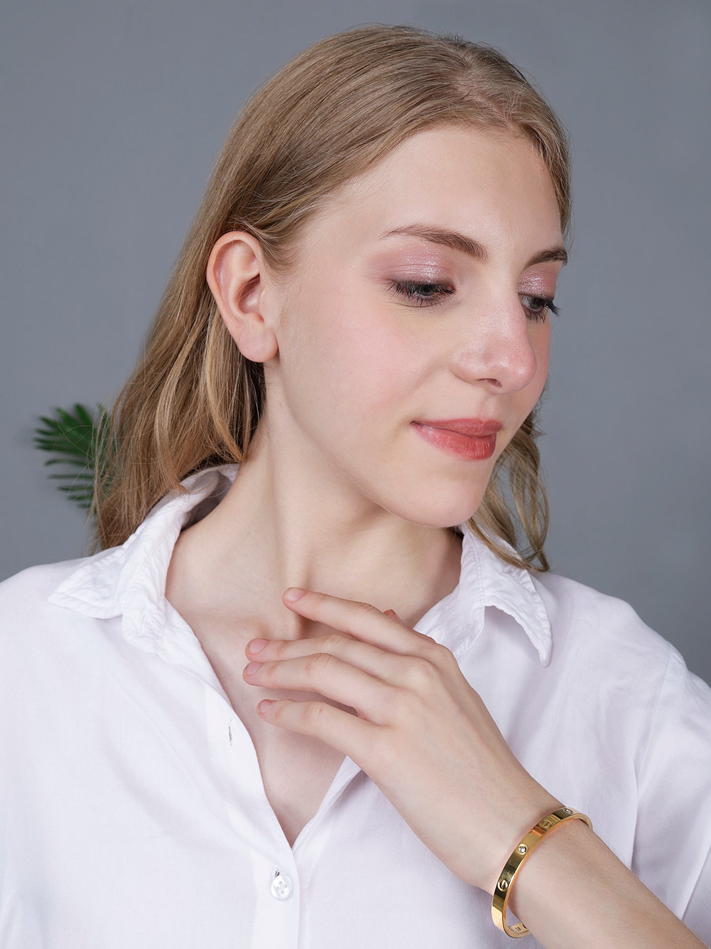 A model wearing a minimalist hand bracelet for women with a polished gold finish and stone accents.