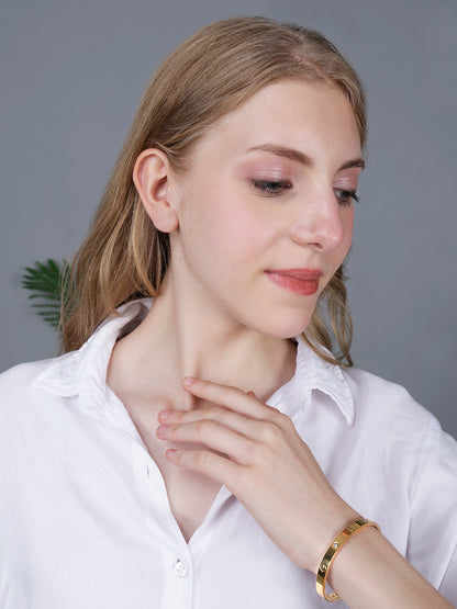 A model wearing a minimalist hand bracelet for women with a polished gold finish and stone accents.