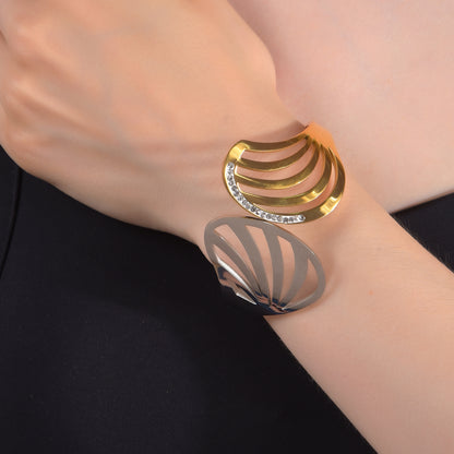 Close-up of a modern hand bracelet for women showcasing a two-tone curved leaf design with embedded stones
