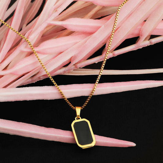 gold necklace for women featuring a thin box chain and a rectangular black pendant, displayed against a black background with soft pink floral accents.
