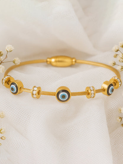 Gold evil eye bracelet for women for daily wear displayed on soft white fabric with flowers.