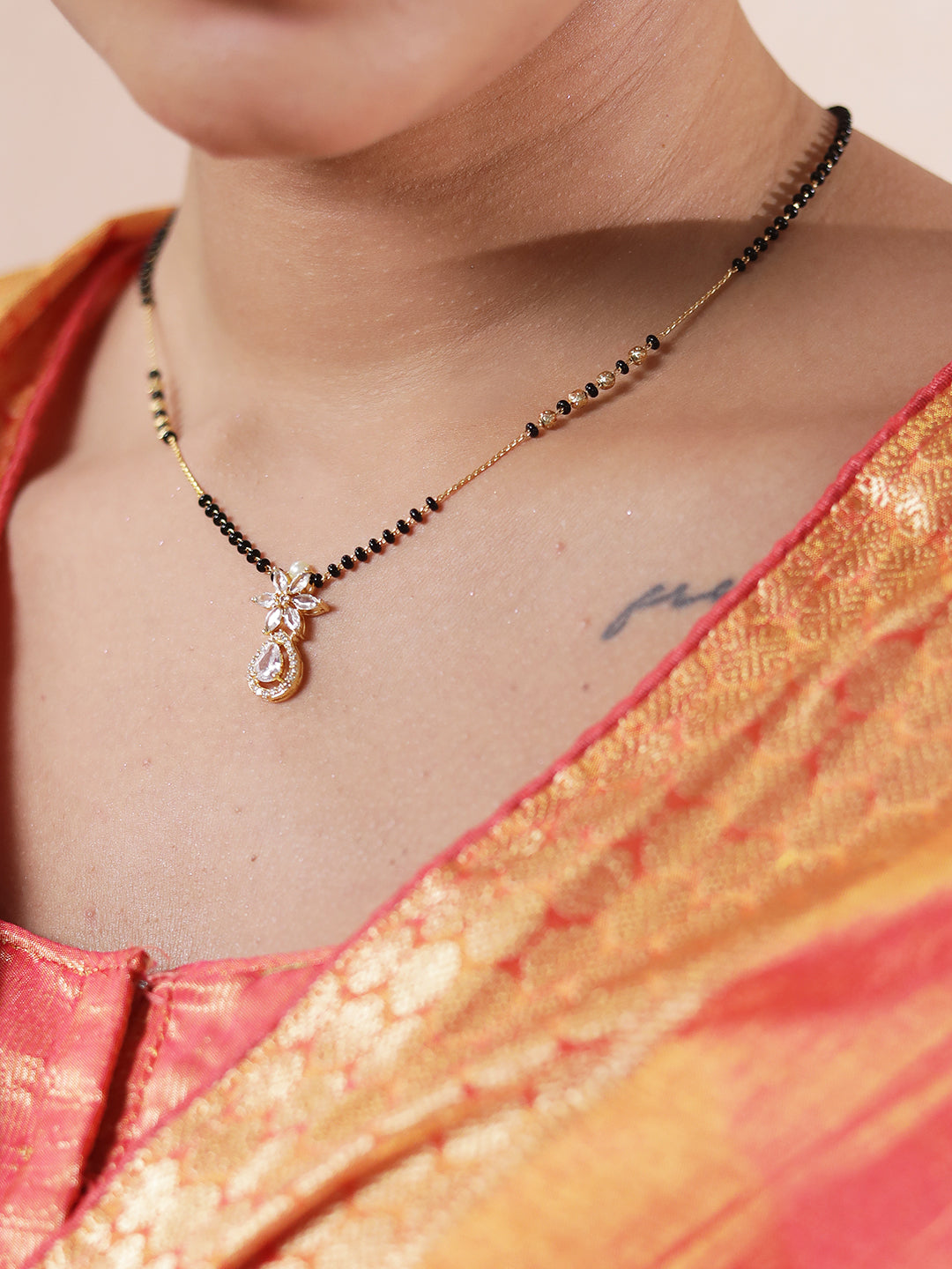 Close-up of mangalsutra pendant design with black beads and a floral gold pendant