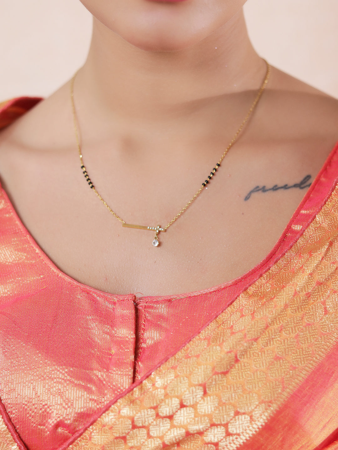 Minimal bar pendant mangalsutra design with gold-tone chain and black beads worn with a traditional saree