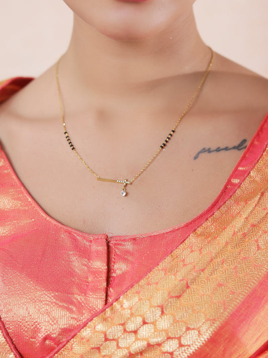Minimal bar pendant mangalsutra design with gold-tone chain and black beads worn with a traditional saree