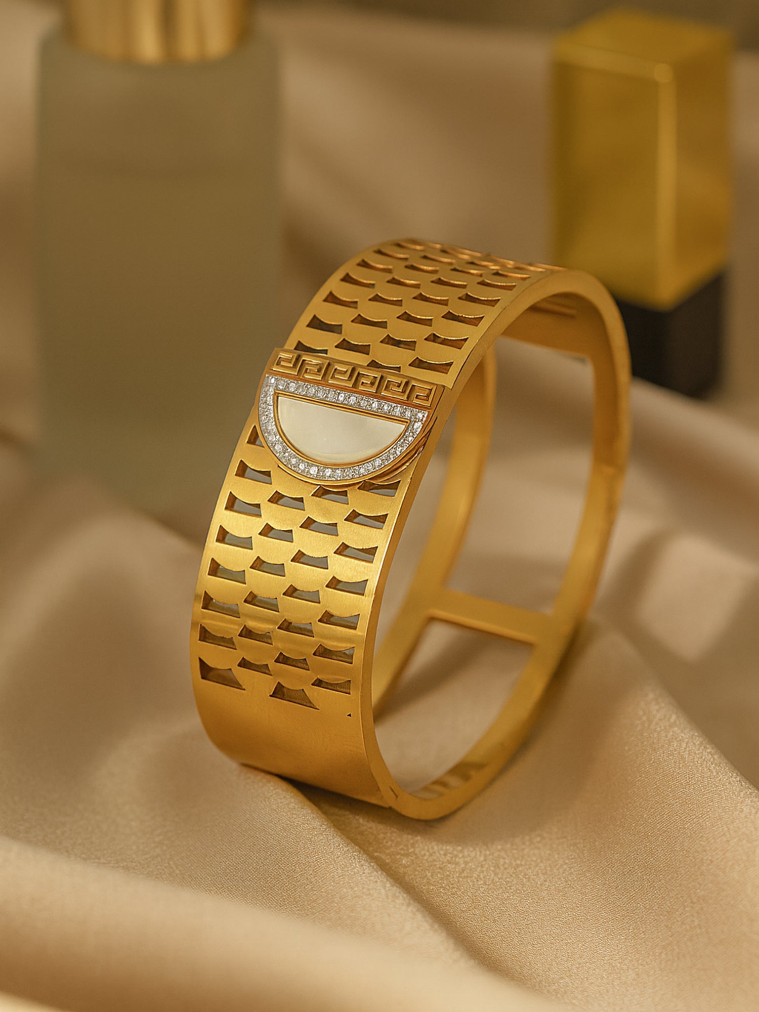 A stylish gold bracelet design for women featuring a D-shaped pearl inlay and intricate cut-out patterns.