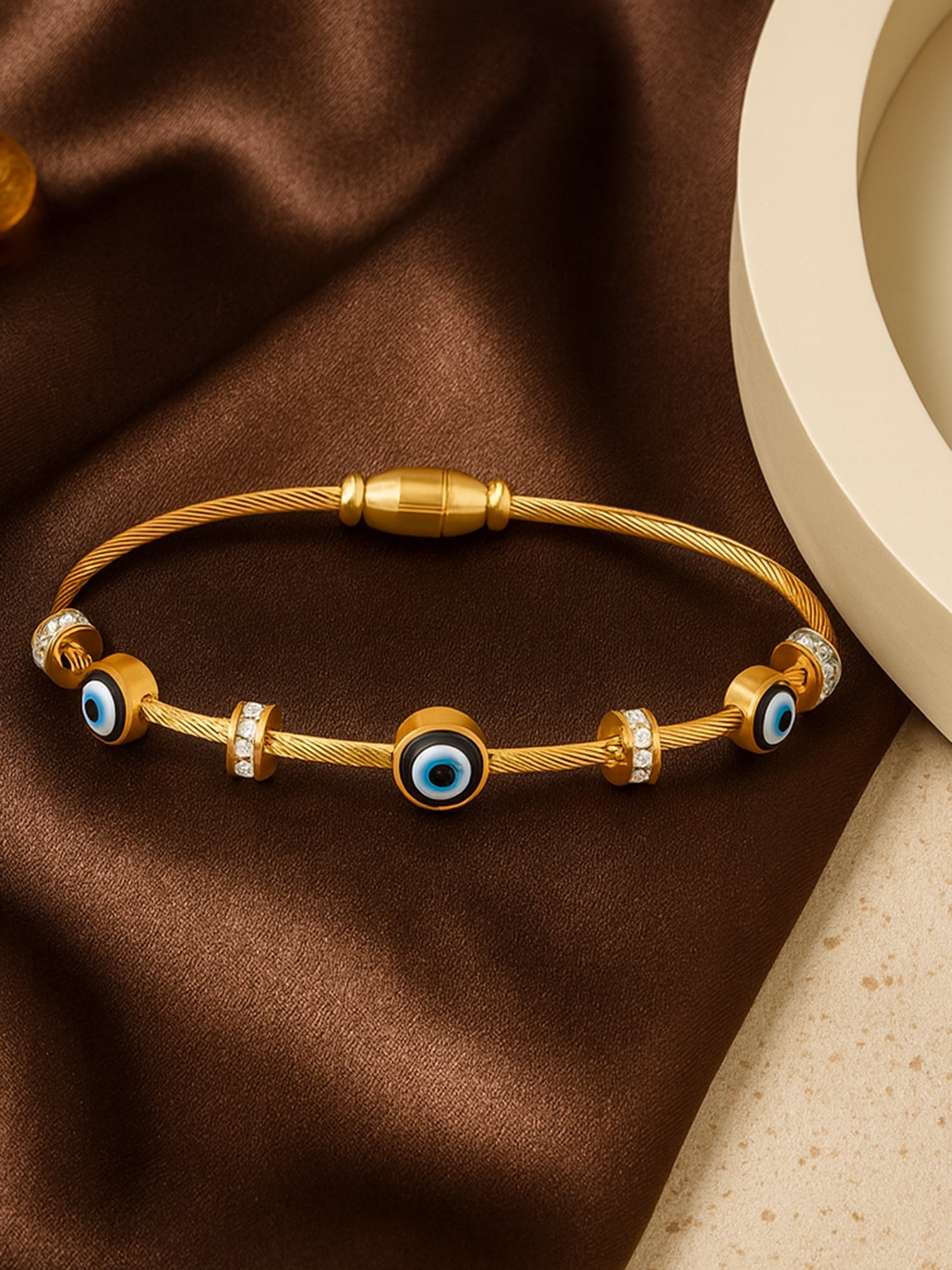 Stylish gold bracelet design for women with a twisted cable band and protective evil eye beads.