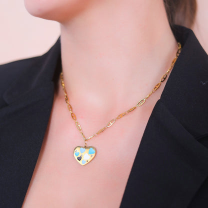 Close-up of a gold chain with pendant featuring multi-colored hearts, styled for professional women's fashion.