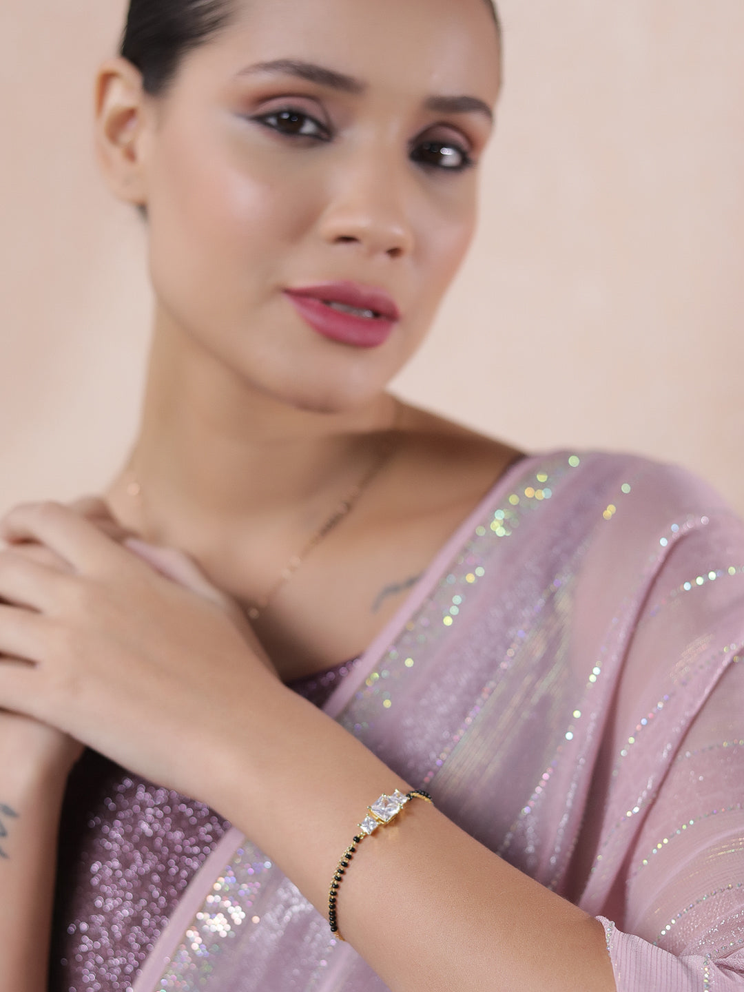 Elegant mangalsutra latest design gold bracelet for women styled with a shimmery pink saree.