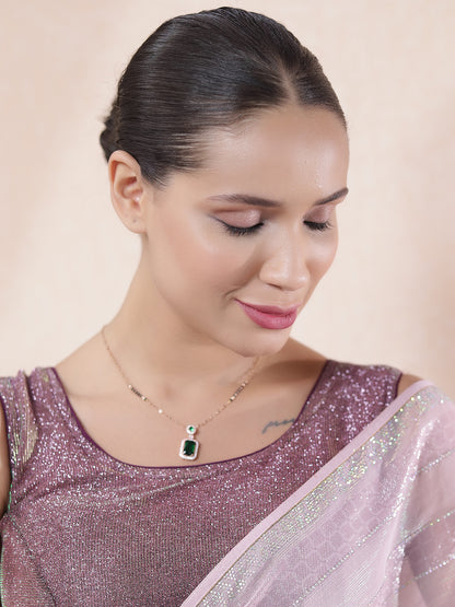 Model wearing the latest mangalsutra design featuring a gold chain with an emerald pendant, styled with a shimmer saree