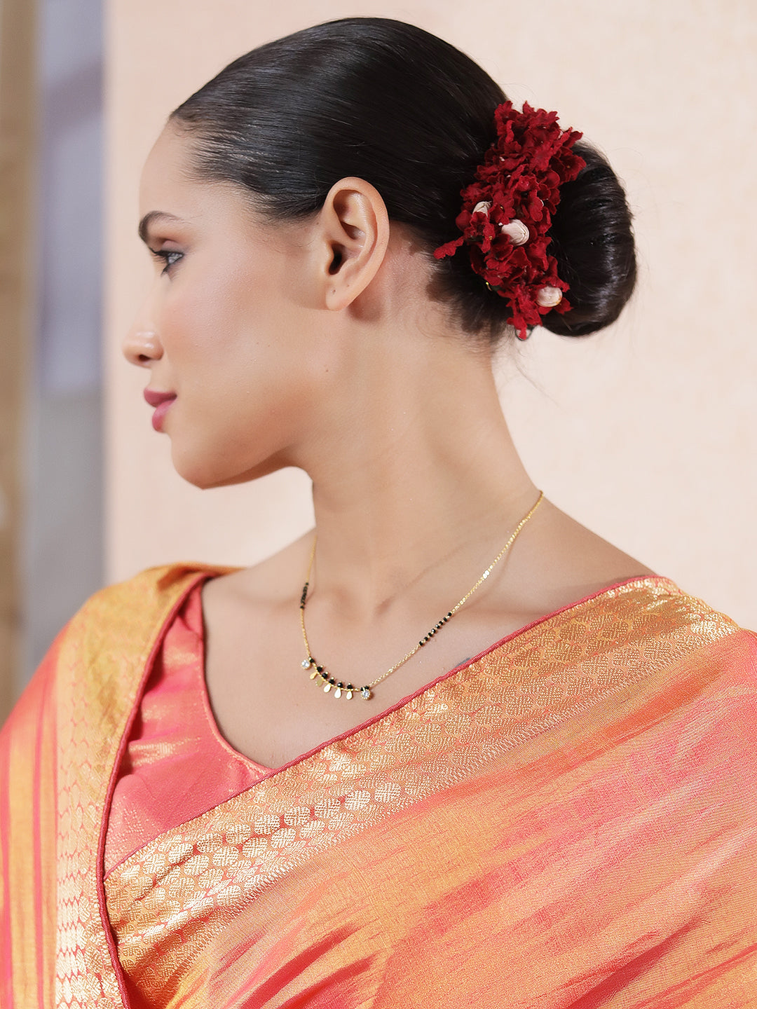 Gold Hindu mangalsutra design with black beads and small gold coin charms worn with traditional saree