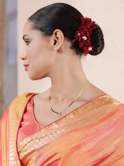 Gold Hindu mangalsutra design with black beads and small gold coin charms worn with traditional saree