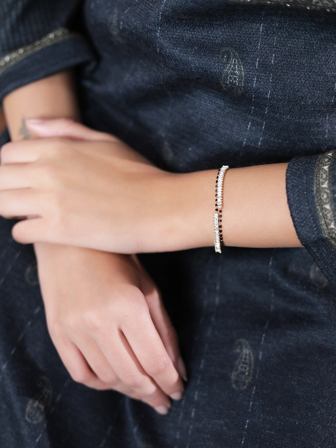 Gold black beads mangalsutra bracelet on woman’s wrist