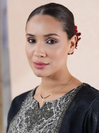 Woman wearing a gold Hindu mangalsutra design with a delicate chain and small pendant, styled with traditional attire