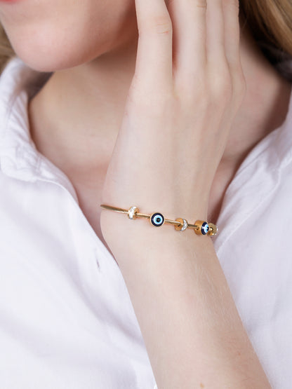 Close up of a gold plated hand bracelet for women worn on a wrist with a white shirt.