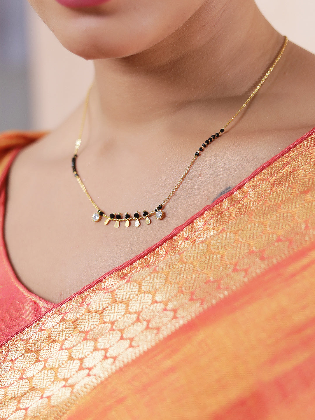 Fancy short mangalsutra design with gold chain, black beads, and small hanging gold charms