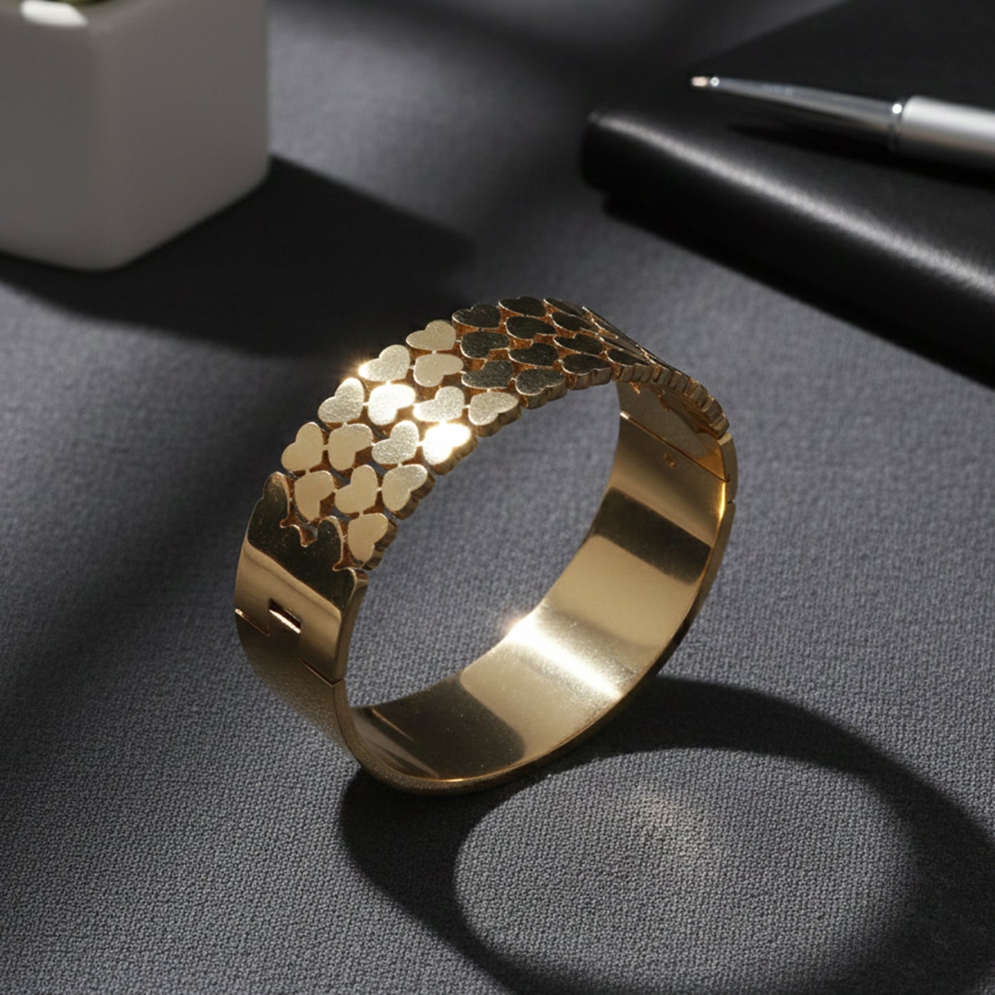 Stylish gold bracelet design for women with polished heart patterns reflecting light on a textured surface