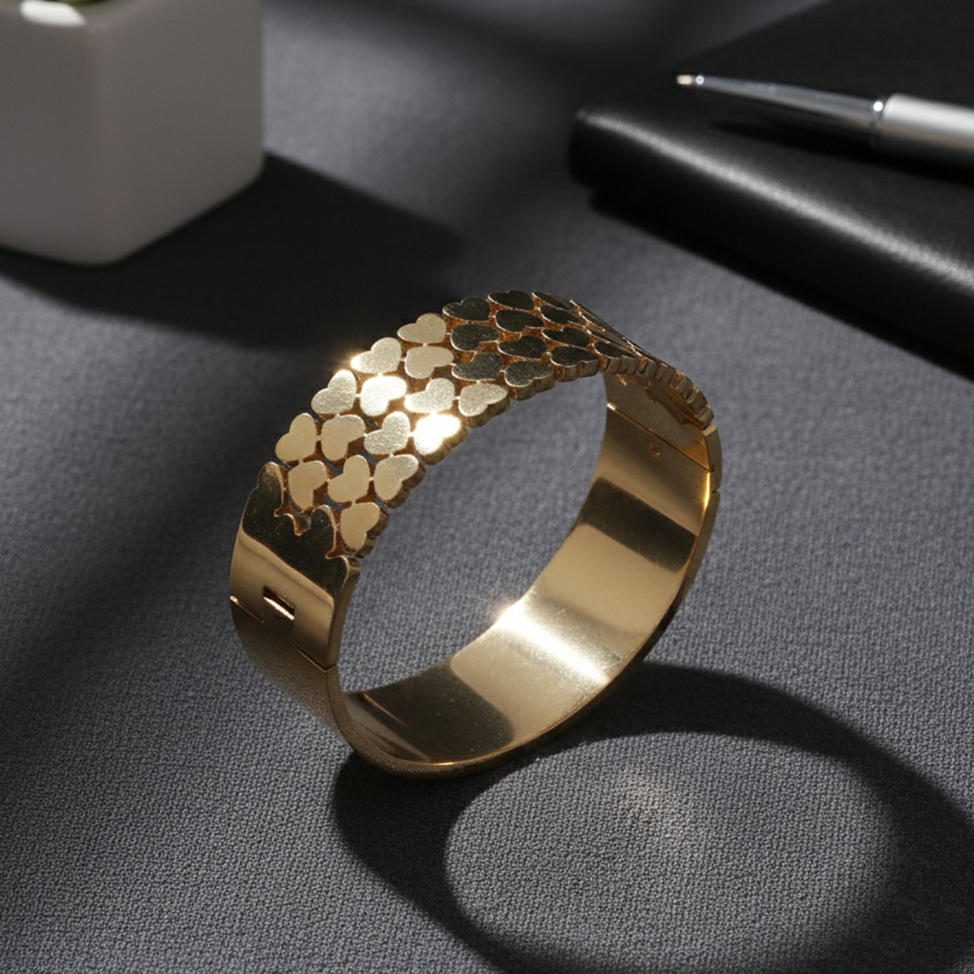 Stylish gold bracelet design for women with polished heart patterns reflecting light on a textured surface