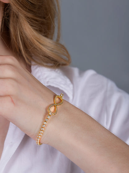 Close-up of a hand bracelet for women showing the detailed gold infinity link and tennis-style chain.