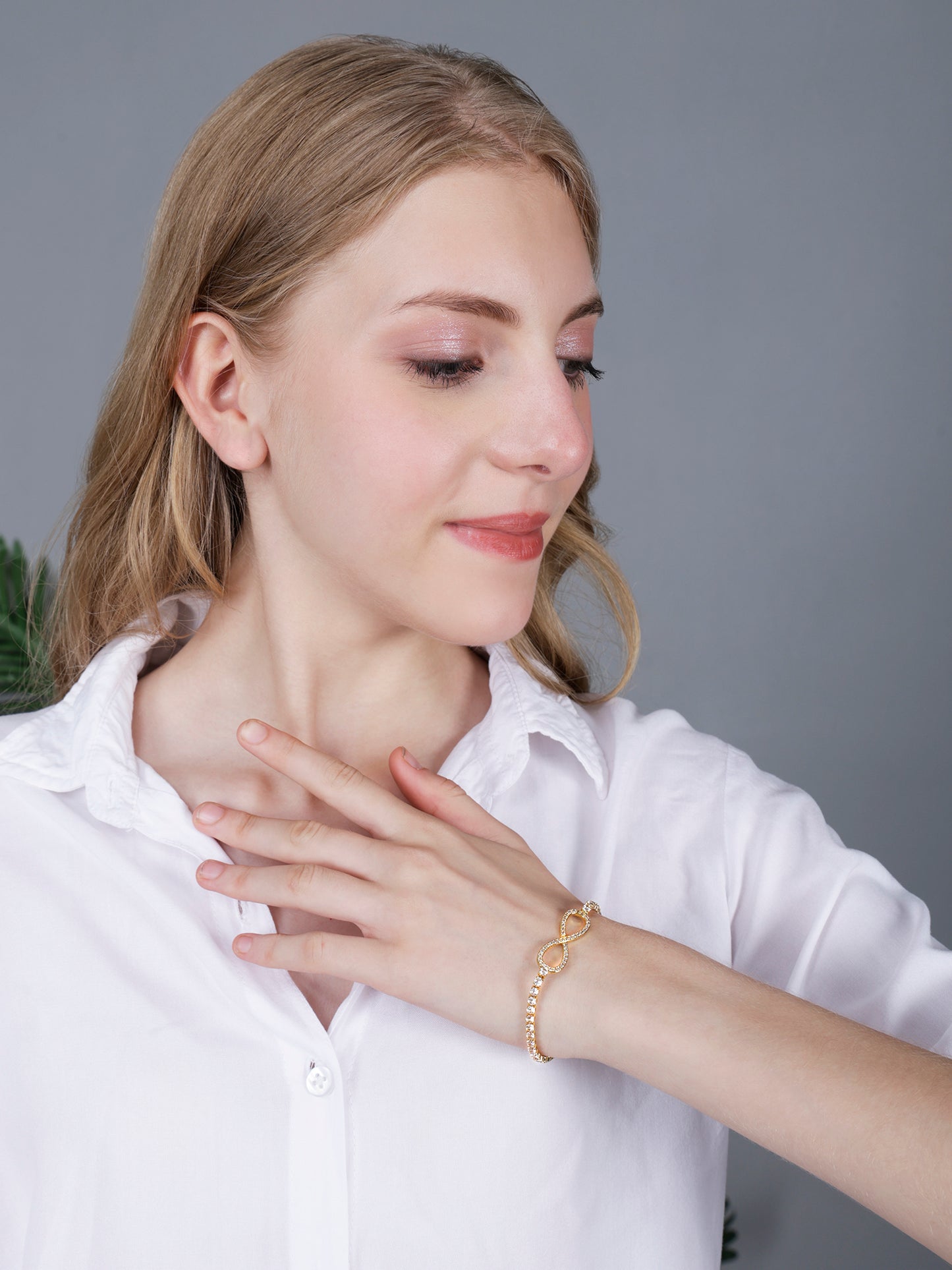 Stylish bracelet for women with infinity charm worn by a model in a white shirt.