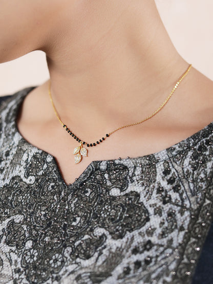 Latest mangalsutra design with black beads, gold chain, and a crystal leaf pendant worn on neckline