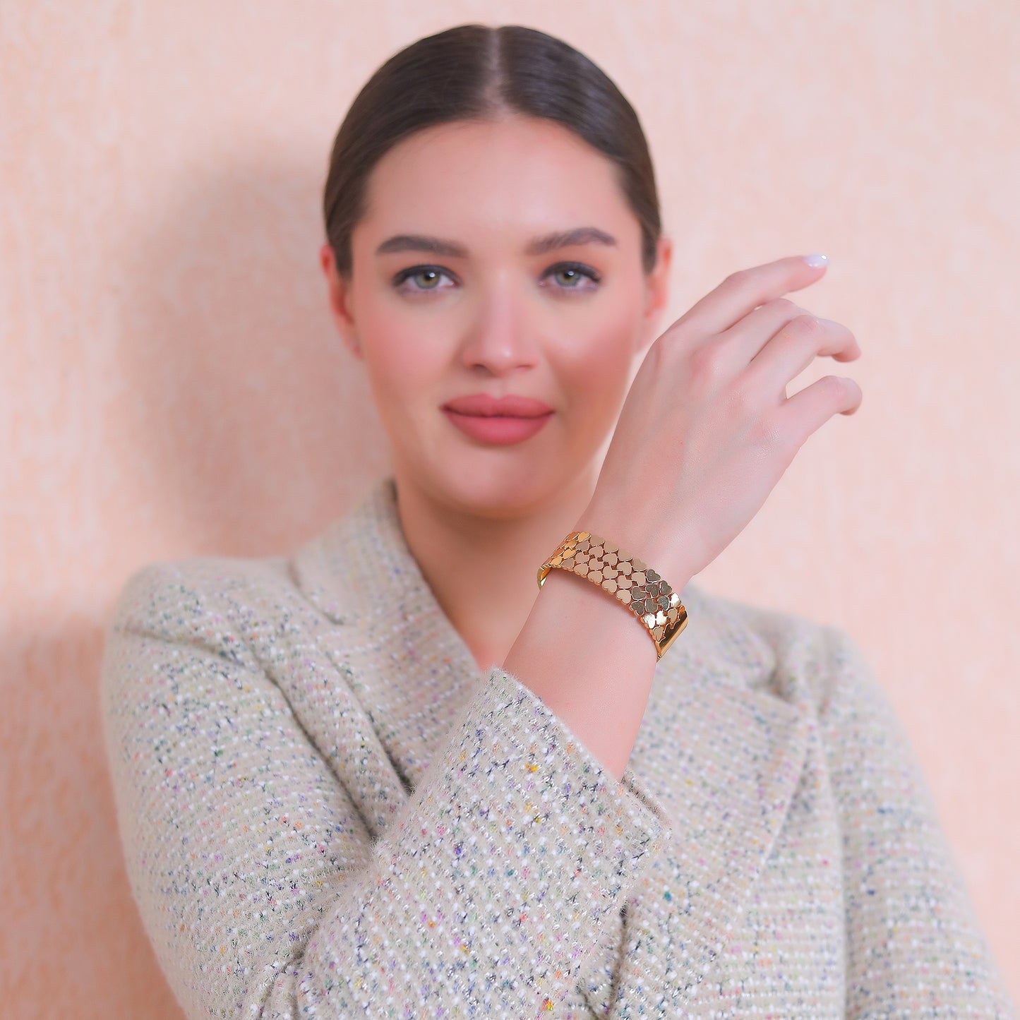 A woman wearing the latest bracelet design featuring a gold heart-link pattern with a professional blazer