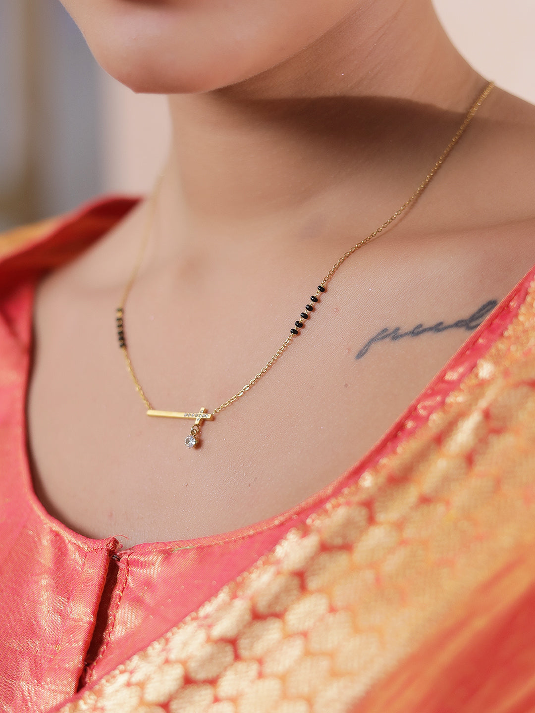 Latest gold mangalsutra design with bar pendant, solitaire drop, and black beads worn with a traditional outfit