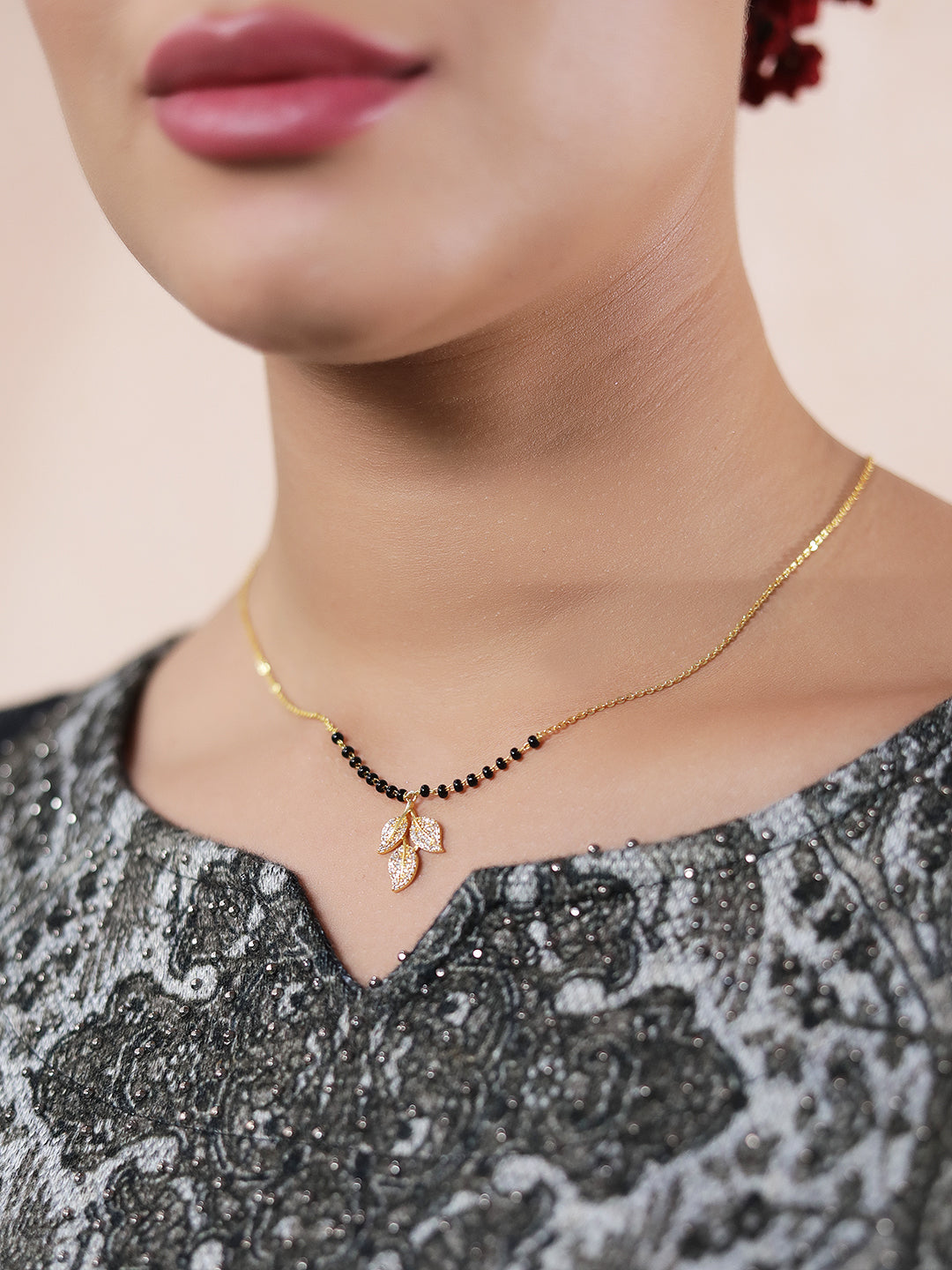 Latest gold mangalsutra design with black beads and crystal leaf pendant worn on neckline
