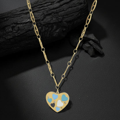 Light weight gold necklace with a decorative heart charm and small crystals, placed on a textured charcoal surface.