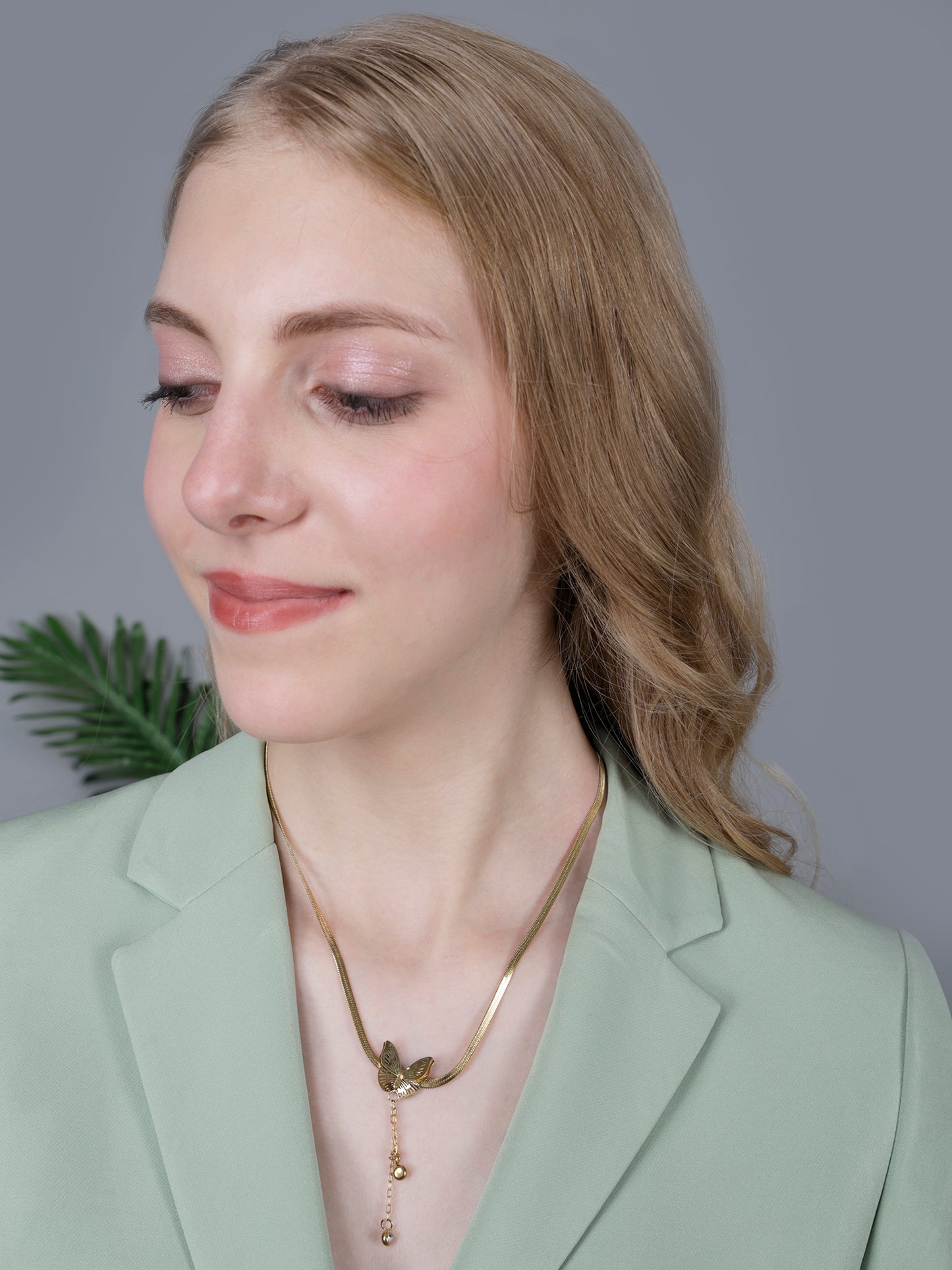 Model wearing light weight gold necklace on a snake chain with matching butterfly stud earrings