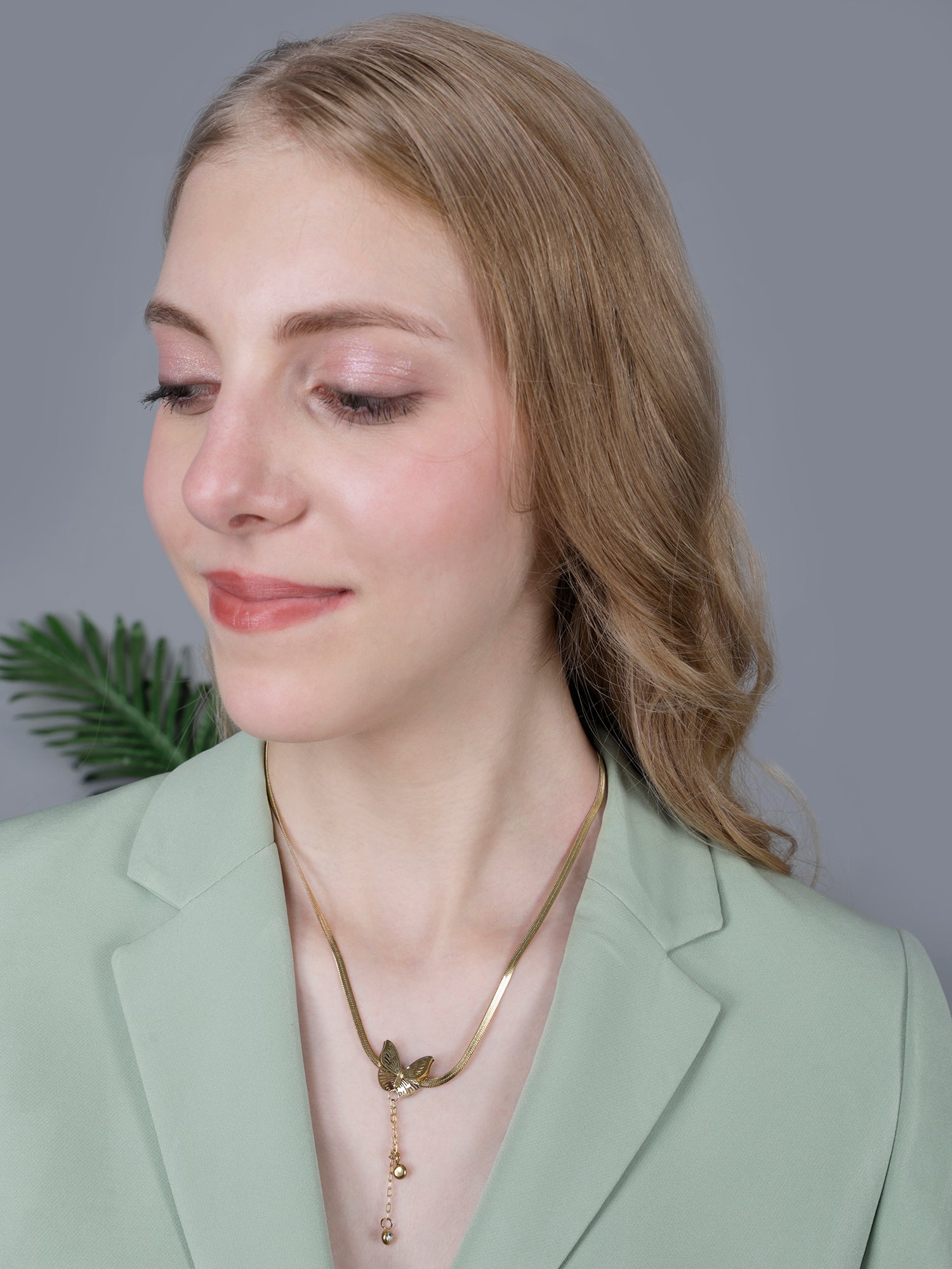 Model wearing light weight gold necklace on a snake chain with matching butterfly stud earrings