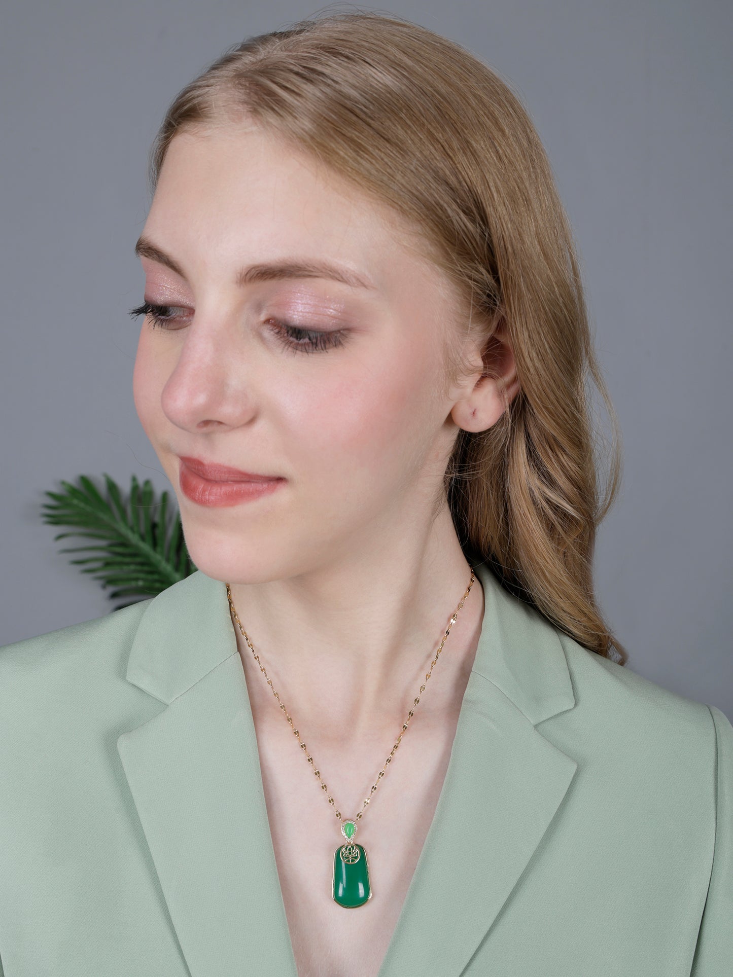 High-quality gold long necklace designs for women with a sophisticated green stone charm and polished gold finish in a lifestyle setting.