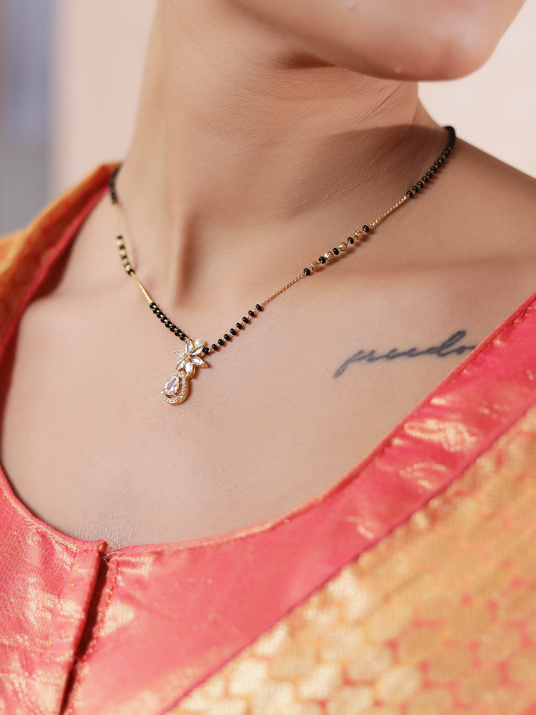 Gold Hindu mangalsutra design with black beads and a delicate CZ pendant worn on neck