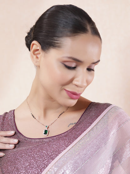 Model wearing a gold mangalsutra pendant design featuring an emerald centerpiece, styled with a shimmer saree.